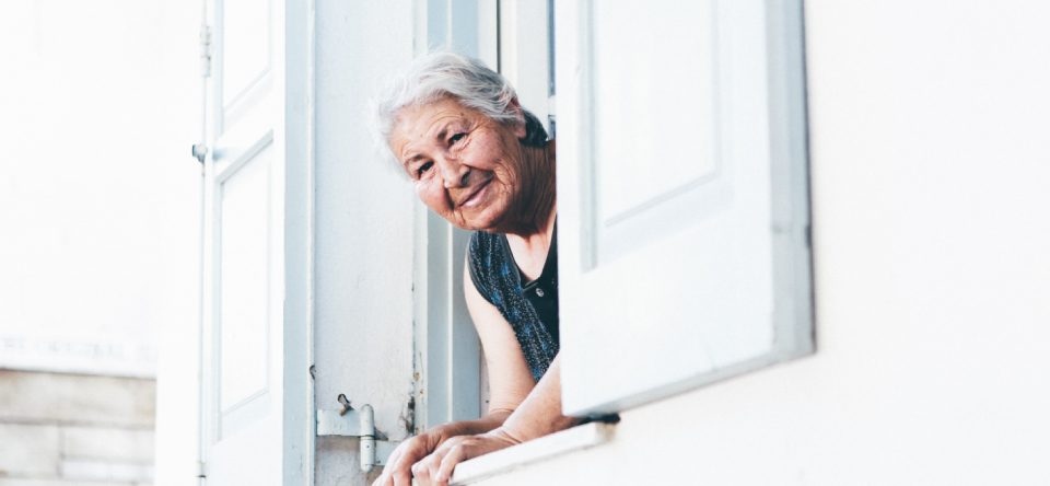 Mujer adulta mayor cuidadora mirando por ventana feliz